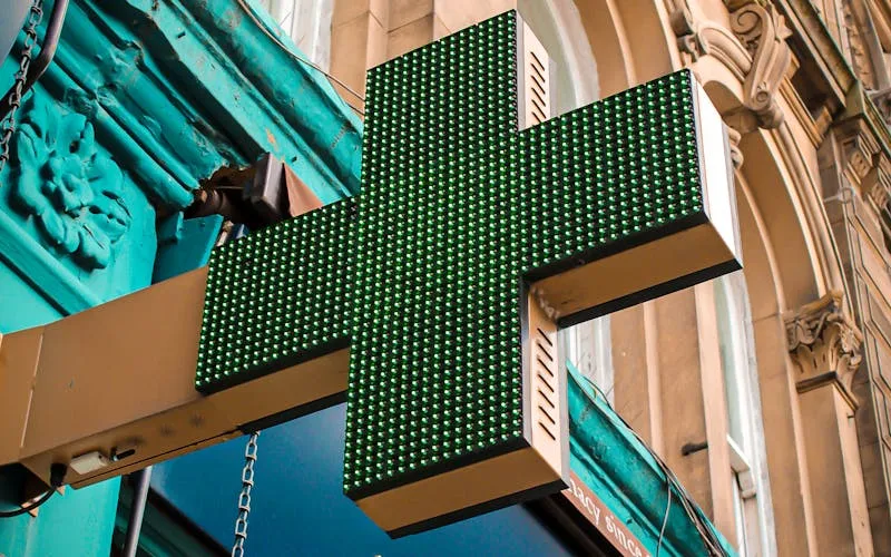 Croix verte LED de pharmacie d'officine sur façade haussmannienne pour les gardes